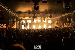 Blick auf eine beleuchtete Festivalbühne und ein dichtes Publikum am Abend.